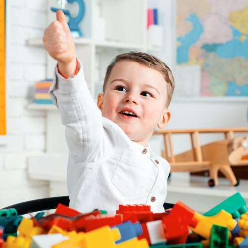Happy smiling boy with thumb up in school. Kid indoors of the classroom. Back to school. Funny pupil in class. Little boy from primary school